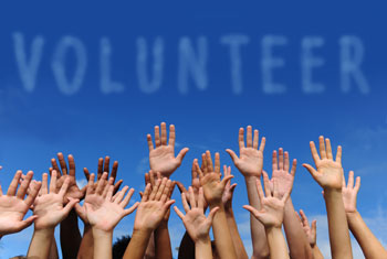 volunteer group raising hands against blue sky background